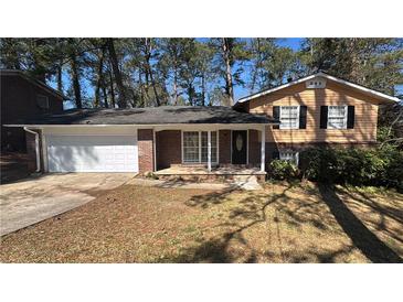 Charming home with brick accents, a well-maintained lawn, and an attached two-car garage at 4100 Seneca Way, Stone Mountain, GA 30083