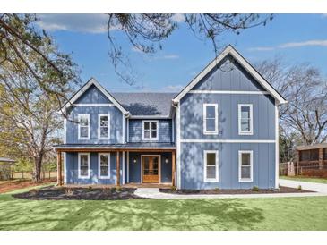 A charming two-story blue home featuring a welcoming front porch and professionally landscaped front yard at 474 Maxwell Rd, Roswell, GA 30075