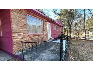 Charming home featuring a brick facade and unique pink accents, complemented by a well-maintained yard at 6247 Green Acres Sw Dr, Covington, GA 30014