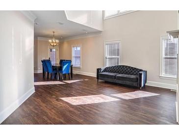 An open-concept living room with a tufted sofa, dining table, and hardwood floors, bathed in natural light at 409 Angier Ne Ct, Atlanta, GA 30312