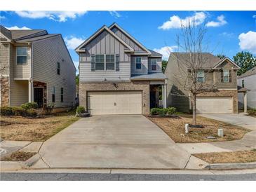 Two-story home showcasing a well-maintained front yard, brick accents, and a two-car garage at 5113 Rapahoe Trl, Atlanta, GA 30339