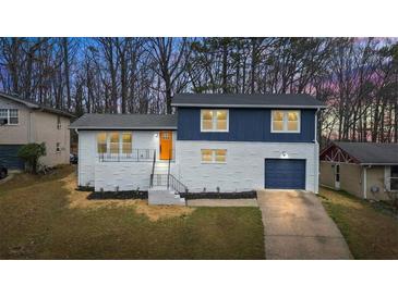 Charming two-story home featuring a white brick facade, blue accents, and a bright orange front door at 3565 Collier Drive Nw Rd, Atlanta, GA 30331