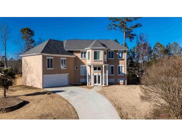 Elegant two-story stucco home with a well-manicured lawn and a paved driveway leading to an attached garage at 4197 Trotters Way Dr, Snellville, GA 30039