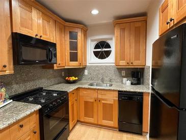 Bright kitchen features wood cabinetry, granite countertops, and modern appliances at 5400 Roswell Rd # K1, Atlanta, GA 30342