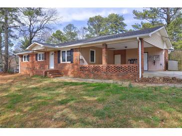 Charming brick home with a covered porch and carport, surrounded by mature trees and a well-maintained lawn at 2924 Vogue Dr, Douglasville, GA 30134