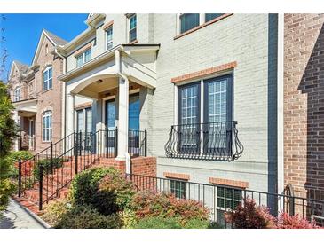 Charming townhome with brick accents, black railings, and colorful landscaping at 327 Alderwood Ln, Atlanta, GA 30328
