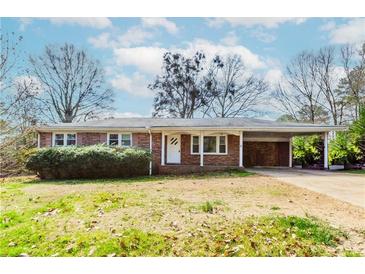 Charming one-story brick home with a covered carport and well-maintained landscaping in a suburban neighborhood at 3951 Lindley Dr, Powder Springs, GA 30127