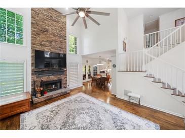 Bright living room boasts a soaring ceiling, large stone fireplace and hardwood floors at 475 Highland Gate Cir, Suwanee, GA 30024