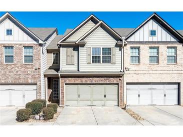 Charming townhome featuring neutral siding, brick accents, and an attached two-car garage at 933 Spicy Oak Dr, Lawrenceville, GA 30044