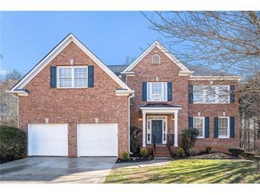Charming brick two-story home with a two-car garage and lush front lawn and dark blue shutters at 2869 Amesbury Nw, Kennesaw, GA 30144