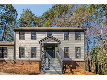 Traditional two-story home featuring a brick foundation and a welcoming front porch entrance with stairs at 3777 Clubhouse Way, Conyers, GA 30094