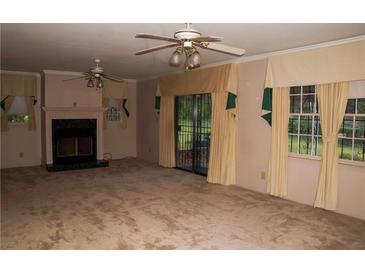 Spacious living room with a fireplace, ceiling fan, and sliding glass doors to the backyard at 3204 Spreading Oak Sw Dr, Atlanta, GA 30311