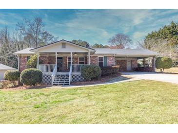 Charming brick home with covered carport, manicured lawn, and inviting front porch at 4031 Pine Needle Dr, Duluth, GA 30096