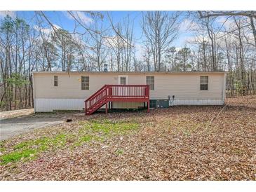 Backyard with a red deck, neutral siding, mature trees, and a level lot at 95 Riverbrooke Trl, Covington, GA 30016