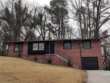 Beautiful brick home with black trim and front yard landscaping and a single car garage at 3230 Jamaica Nw Rd, Atlanta, GA 30318