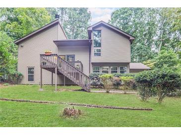 Charming home backyard featuring a wooden deck with stairs and lush greenery at 3625 N Berkeley Lake Nw Rd, Berkeley Lake, GA 30096