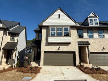 A beautiful townhome showcasing light brick and a two-car garage, set against a bright blue sky at 3904 Allegretto Cir # 50, Atlanta, GA 30339