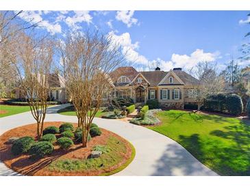 Stately home with a circular drive, lush landscaping, and a welcoming facade under a blue, cloudy sky at 3128 Lower Roswell Rd, Marietta, GA 30068