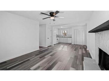 Bright living room boasts modern gray flooring, a ceiling fan, and an open floorplan leading to the kitchen at 2571 Hamill Dr, Buford, GA 30519
