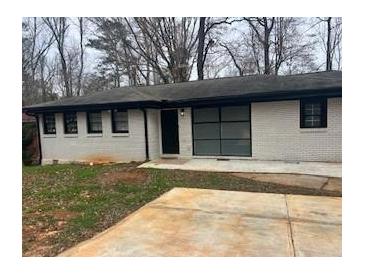 Charming single-story home with a painted brick facade and modern black trim, complemented by a spacious driveway at 3490 Primrose Pl, Decatur, GA 30032
