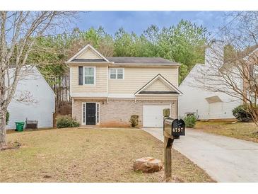 Charming two-story home featuring a well-manicured lawn and a one car garage at 6797 Mahonia Pl, Lithonia, GA 30038