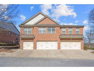 Brick townhome with three garage doors and traditional architecture under a blue sky at 805 Pleasant Hill Rd # 171, Lilburn, GA 30047