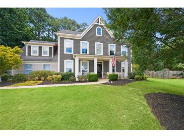 Charming two-story home with manicured lawn, inviting front porch, and a mix of brick and siding accents at 3460 Trow Creek Ln, Cumming, GA 30040