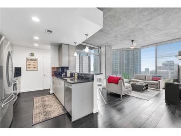 Bright living space featuring hardwood floors, modern kitchen, and floor-to-ceiling windows with city views at 860 Peachtree Ne St # 1502, Atlanta, GA 30308