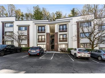 Modern condo building with parking in front and mature trees surrounding the property at 1445 Monroe Ne Dr # F12, Atlanta, GA 30324