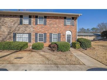 Two-story brick townhome features tidy landscaping, a concrete walk and a dark-colored front door at 413 Northdale Ct, Lawrenceville, GA 30046