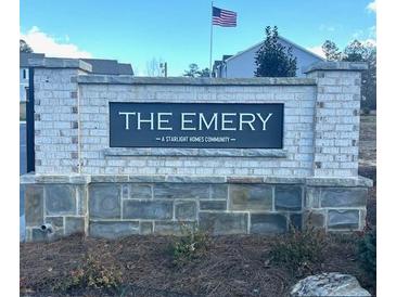 Stone community sign for The Emery, a Starlight Homes Community, topped with an American flag at 206 Gillis Sw Way, Villa Rica, GA 30180