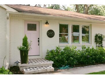 Charming front entrance with a pink door, patterned tile steps, and lush landscaping, creating curb appeal at 545 Woodale Se Dr, Smyrna, GA 30080