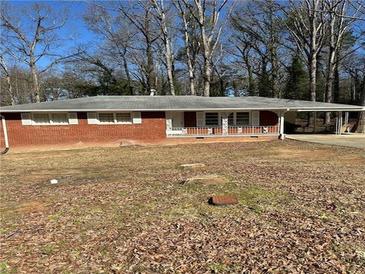 Single story brick home with small porch and carport surrounded by trees at 6756 Brookwood Cir, Jonesboro, GA 30043