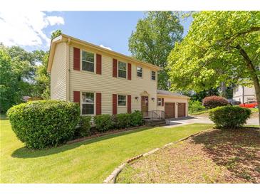 Charming two-story home with a well-manicured lawn and an attached two-car garage, plus red shutters at 5678 Fern Creek Sw Dr, Lilburn, GA 30047