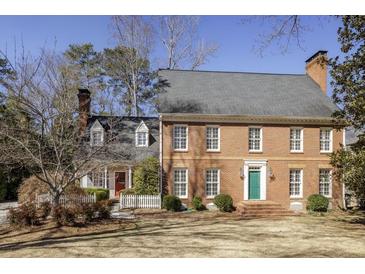 Charming brick two-story home with a well-manicured lawn, and a colorful front door at 270 Grapevine Run, Sandy Springs, GA 30350