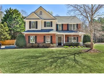 Charming two-story home with a brick facade, manicured lawn, and mature trees, exuding classic elegance and curb appeal at 705 Chanson Sw Dr, Marietta, GA 30064
