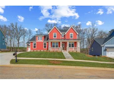 Charming two-story red home featuring a welcoming front porch and manicured lawn at 4039 Andover Cir, Mcdonough, GA 30252