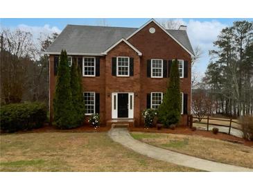 Charming two-story brick home with manicured lawn, mature evergreens, and walkway leading to the front door at 1835 Big Haynes Ct, Grayson, GA 30017