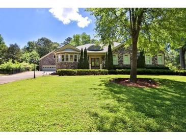 Charming home featuring a stone facade, lush landscaping, and an attached two-car garage at 716 Counsel Ne Dr, Marietta, GA 30068