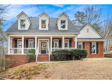 Charming red brick home with a welcoming front porch, dormer windows, and well-maintained landscaping at 3740 Cannonwolde Dr, Snellville, GA 30039