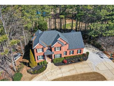 Stately two-story brick home featuring a well-manicured lawn and a circular driveway nestled among mature trees at 4014 Ironhill Ln, Woodstock, GA 30189