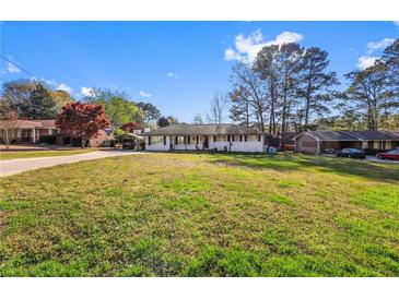 Charming one-story home with a lush green lawn and mature trees, showcasing its curb appeal at 409 Shannon Way, Lawrenceville, GA 30044