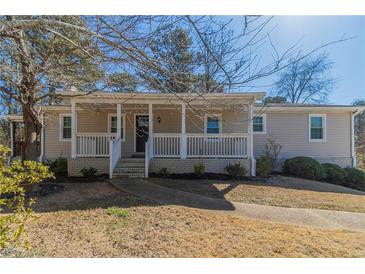 Charming single-story home featuring a covered front porch, a well-manicured lawn, and professional landscaping at 5498 Balmoral Dr, Douglasville, GA 30135
