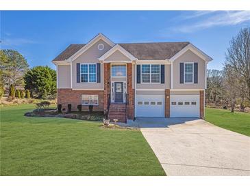 Charming two-story home featuring a brick facade, two-car garage, and well-manicured lawn at 4125 Mark Todd Ct, Hoschton, GA 30548