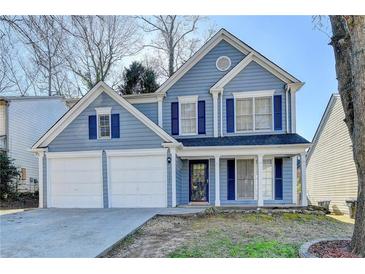 Charming two-story home with blue siding, double garage, and well-maintained front yard at 1064 Wenham Ln, Lawrenceville, GA 30044