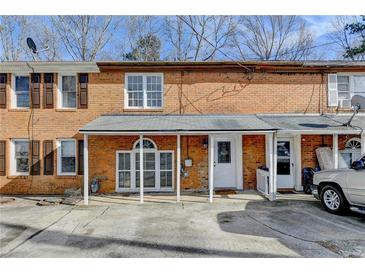 Brick townhome with covered front porch and parking, showcasing classic architectural details at 933 Carla Pl, Norcross, GA 30093