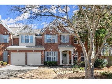 Charming brick townhome featuring a two-car garage and manicured front yard at 913 Thornington Pl, Roswell, GA 30075