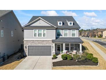 Charming two-story home with stone accents, a gray garage door, and manicured landscaping at 500 Anfield Dr, Woodstock, GA 30188