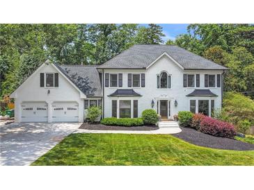 Stunning two-story traditional home featuring a manicured lawn and attached two-car garage at 7010 Hunters Knl, Atlanta, GA 30328