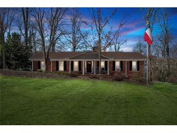 Charming brick home with well-manicured lawn and a flag pole in the front yard against a colorful sky at 3250 N Embry Cir, Atlanta, GA 30341